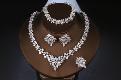 Silver jewelry set including necklace, bracelet, and earrings on a brown stand.