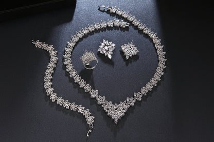 Silver jewelry set including necklace, bracelet, ring, and earrings on a dark surface