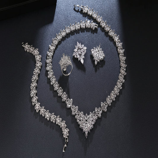 Silver jewelry set including necklace, bracelet, ring, and earrings on a dark surface