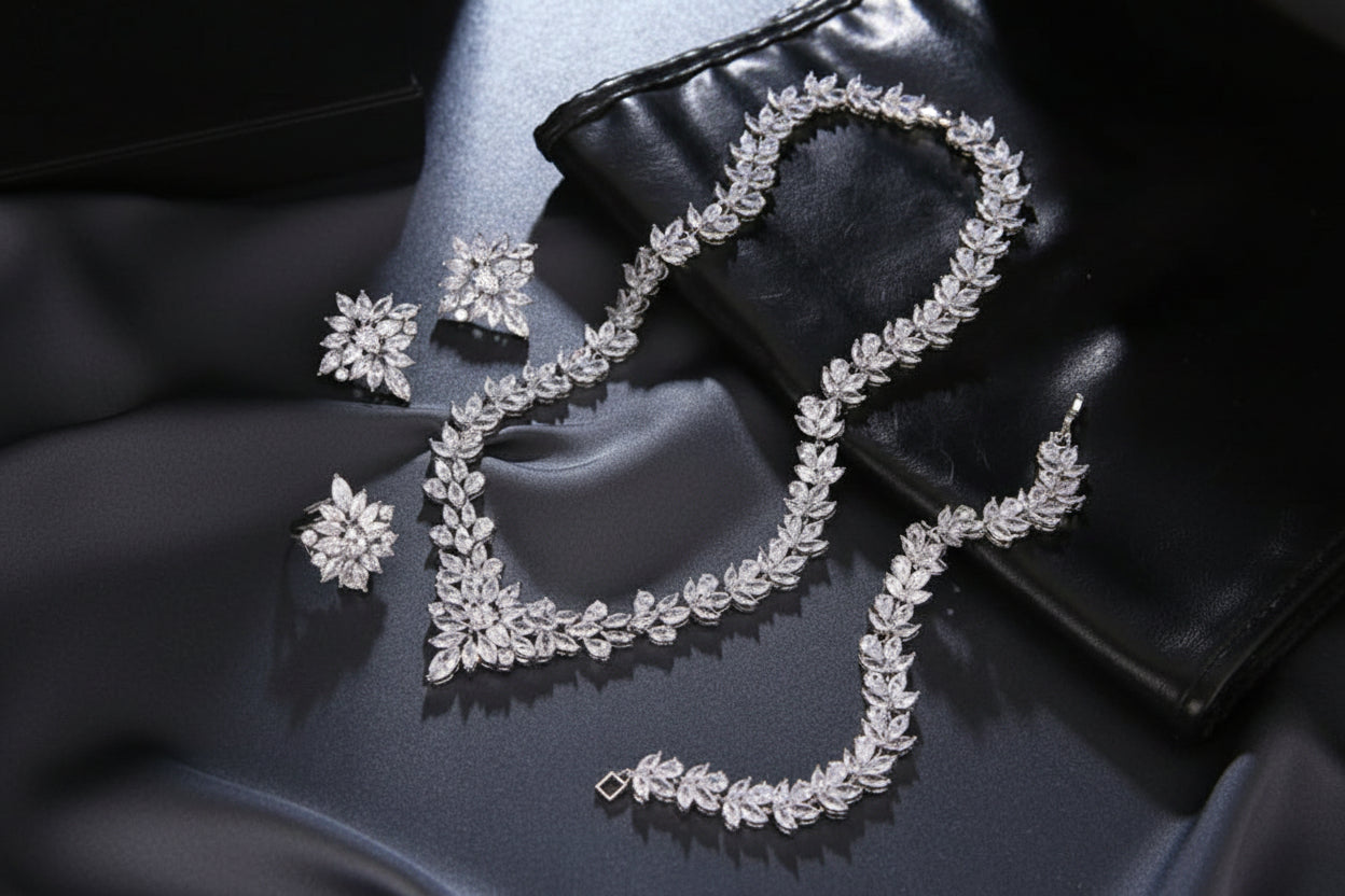 Silver jewelry set including necklace, earrings, and ring on a dark surface