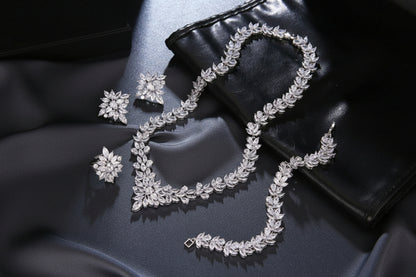 Silver jewelry set including necklace, earrings, and ring on a dark surface