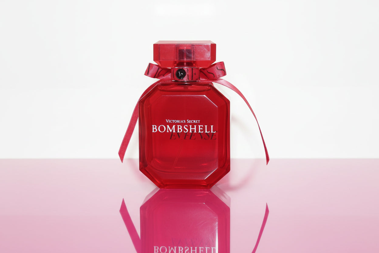 Red 'Bombshell' perfume bottle with a ribbon on a wooden surface