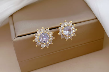 Pair of gold and gemstone earrings on a beige jewelry box