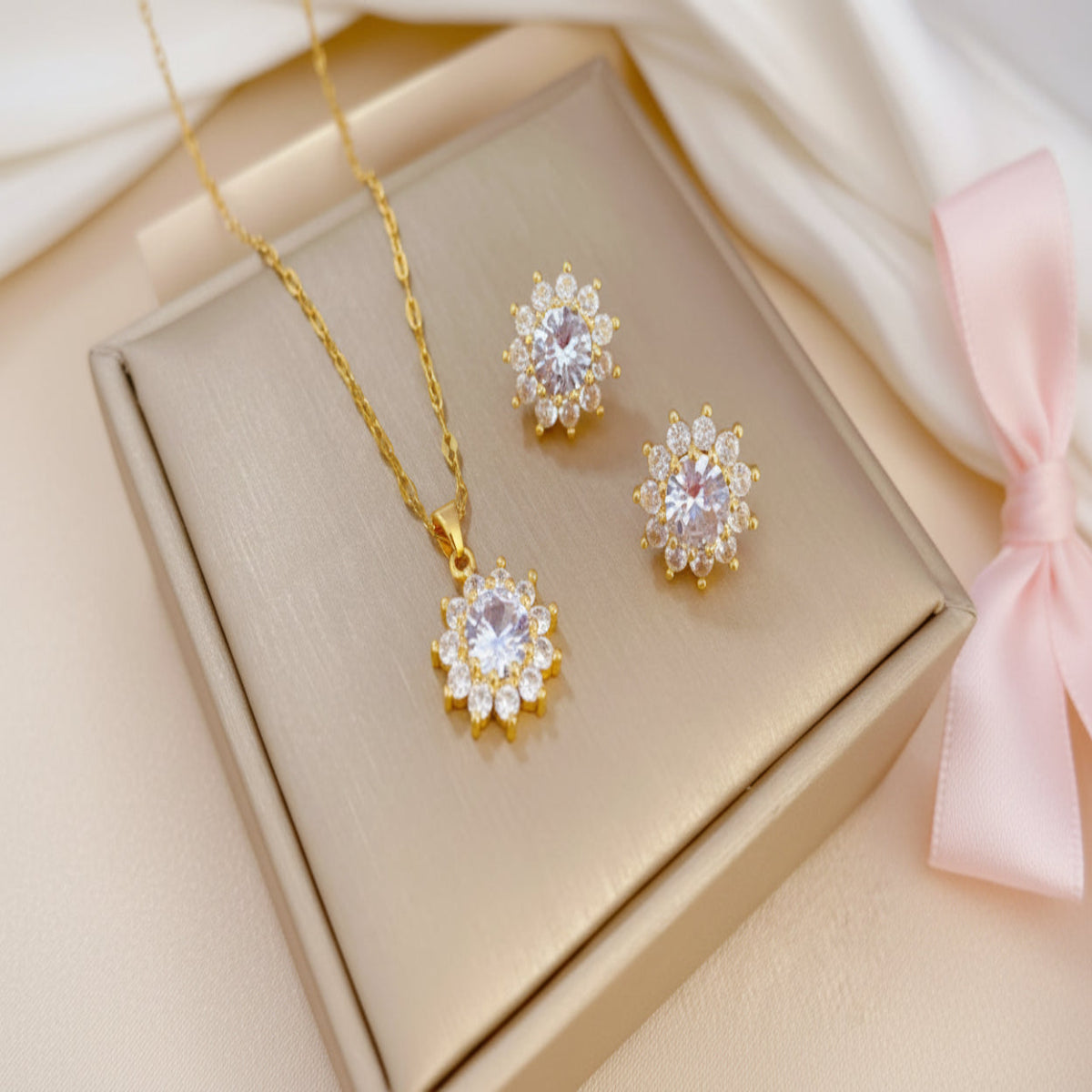 Gold necklace and earrings with diamond-like stones on a beige surface
