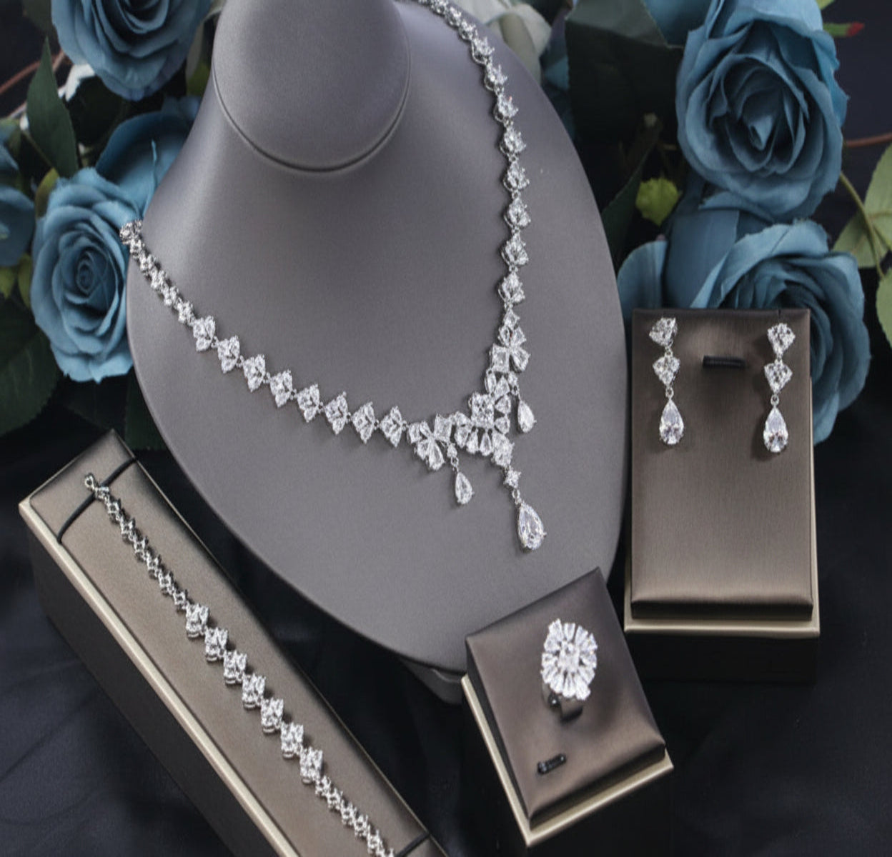 Jewelry set with necklace and earrings on a brown stand with blue flowers in the background