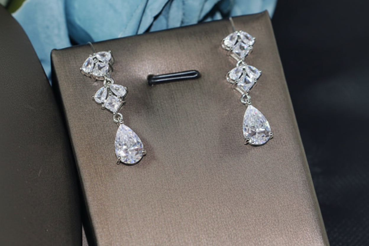 Pair of diamond earrings on a brown box with a blue fabric background