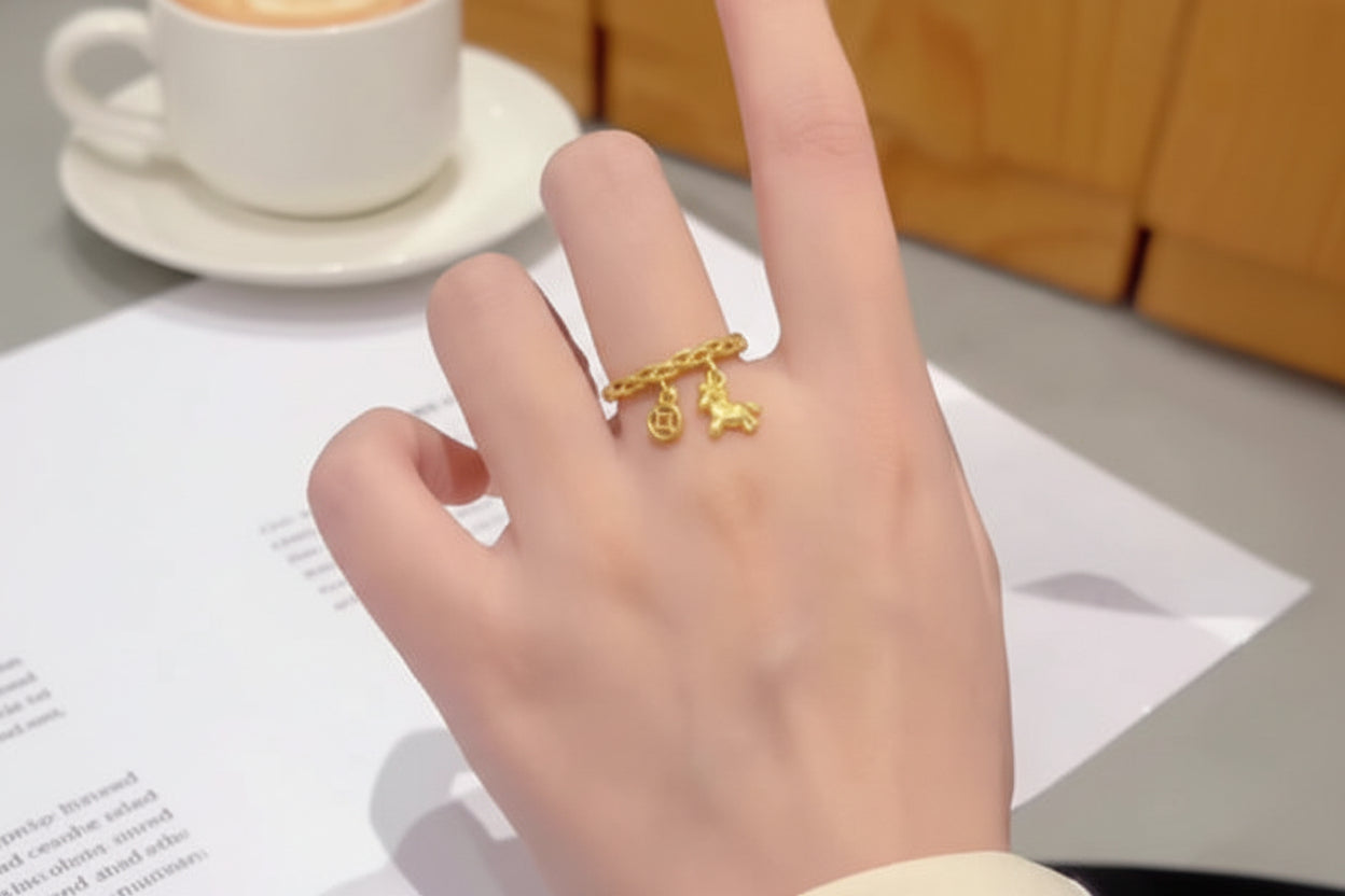 Gold ring with charms on a hand, blurred background